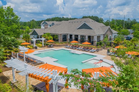 a swimming pool with orange umbrellas in front of a house